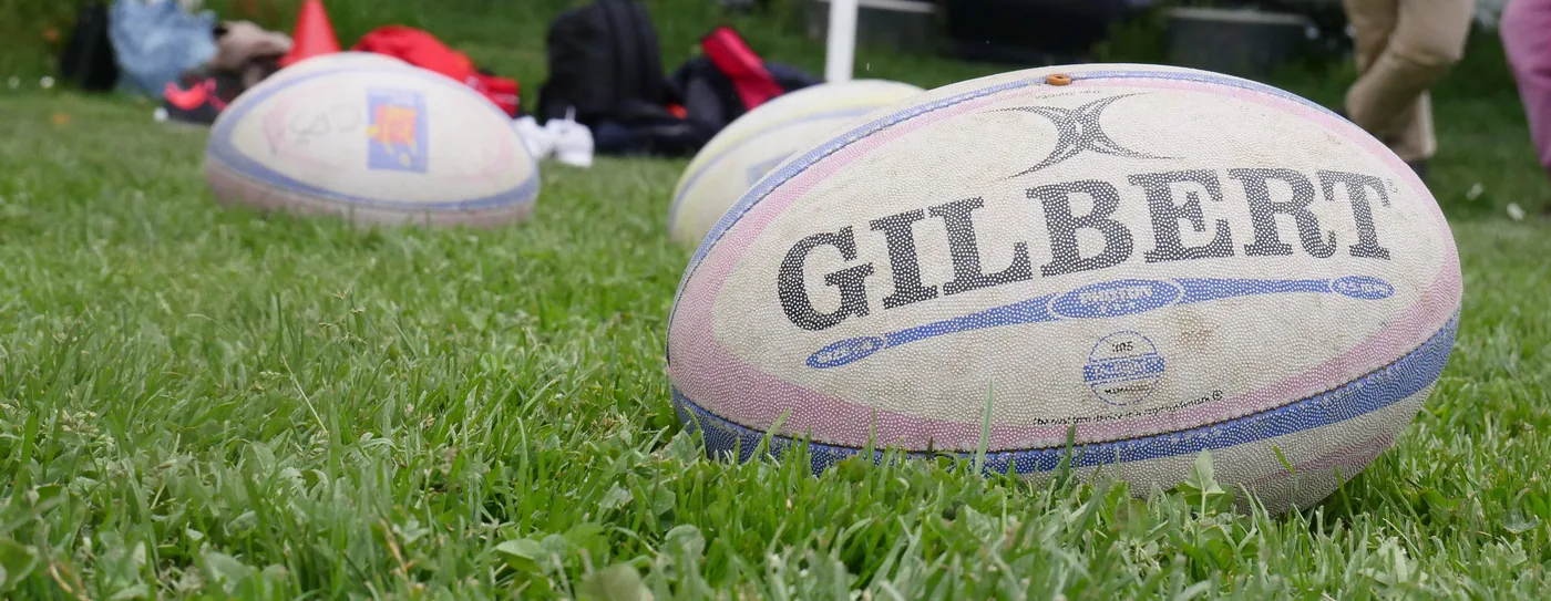 Un ballon de rugby Gilbert posé sur la pelouse du terrain