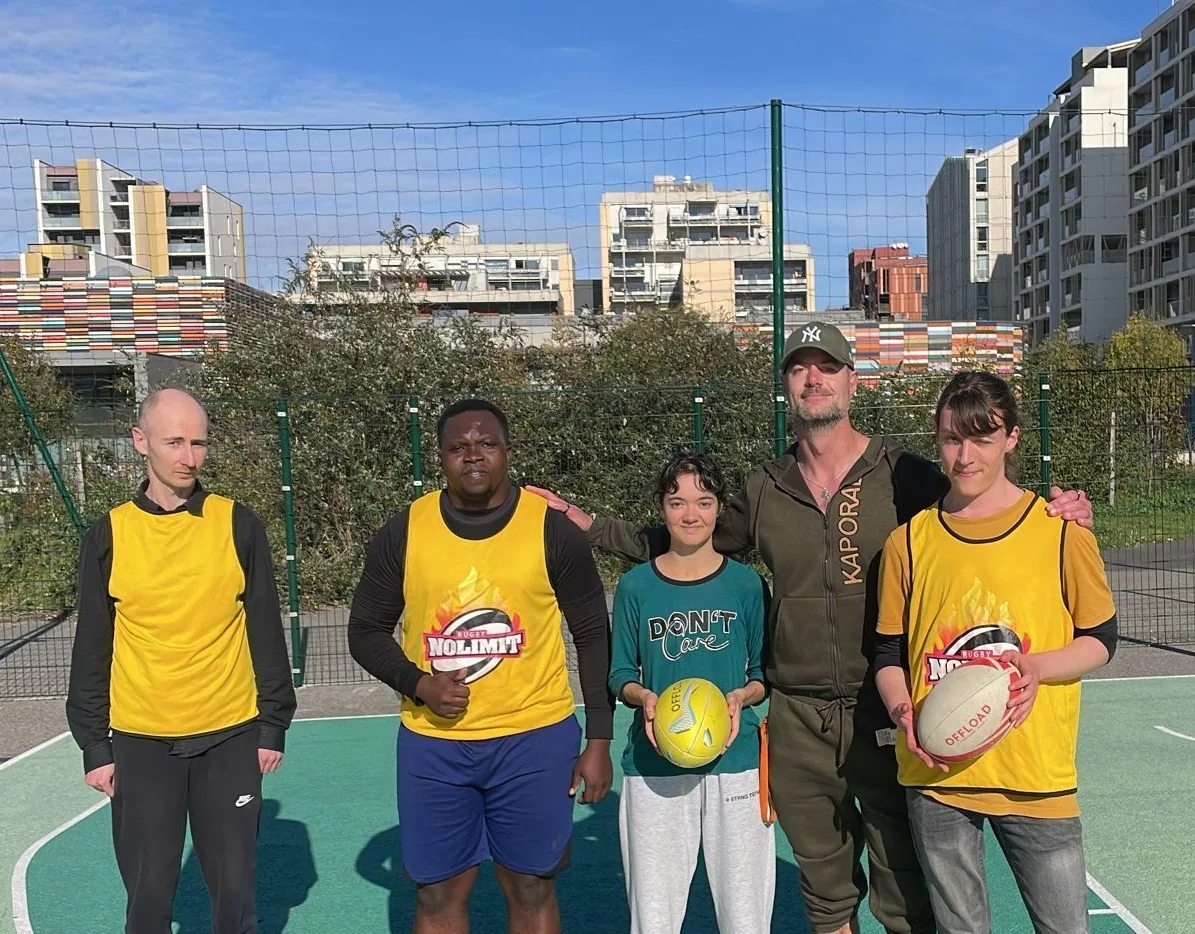 Un groupe de participants pose avec des ballons sur un city-stade de quartier